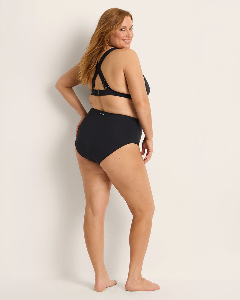 Woman wearing a Fearless supportive bust and high waist black bikini against a plain background.