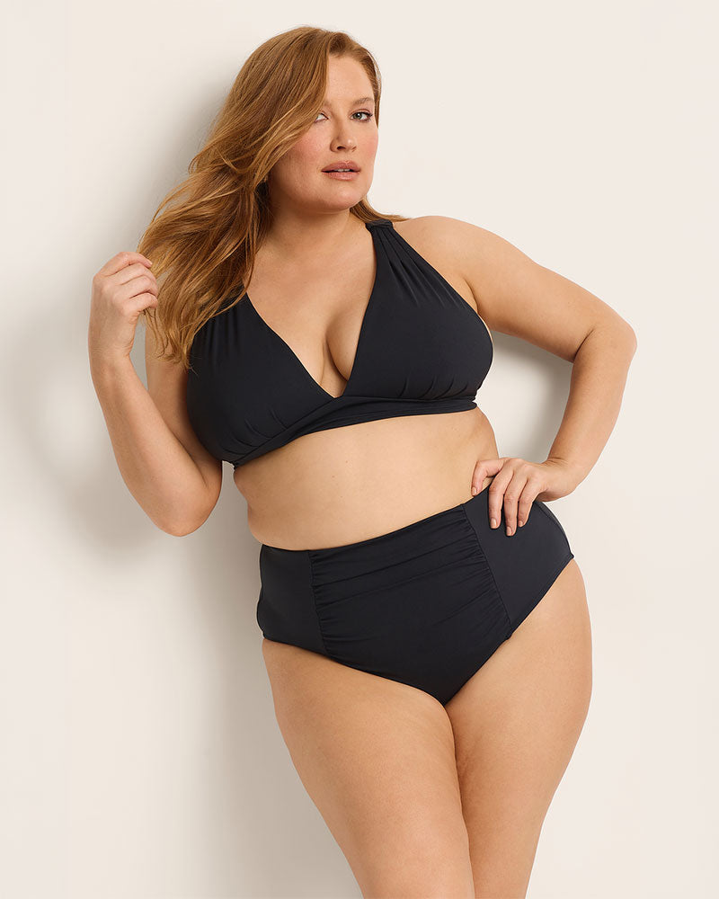 Woman wearing a black bikini set against a plain background