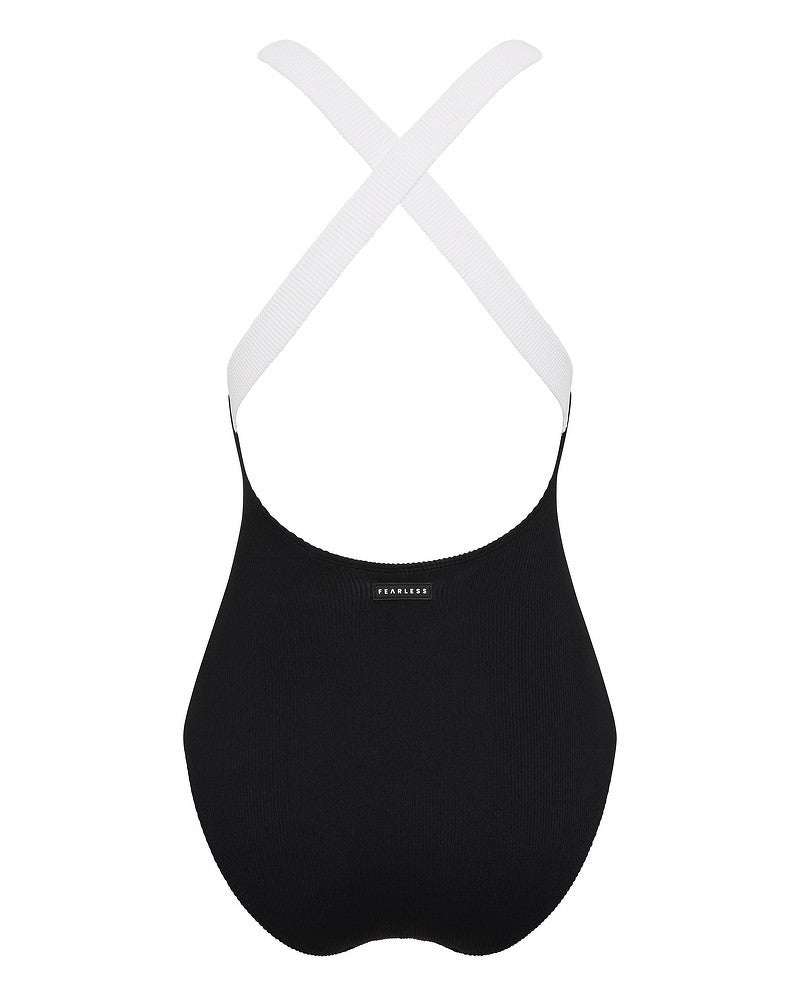 A black, seamless sports bra with white elastic straps crossed at the back and the word FEARLESS printed in small white letters on the front.