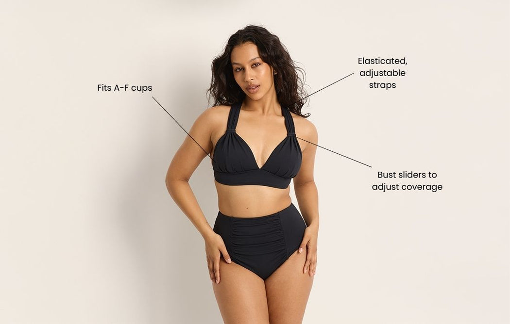 Woman wearing a black bikini set with high-waisted bottoms. Text points to features: Fits A–F cups, Elasticated, adjustable straps, and Bust sliders to adjust coverage. Neutral background.