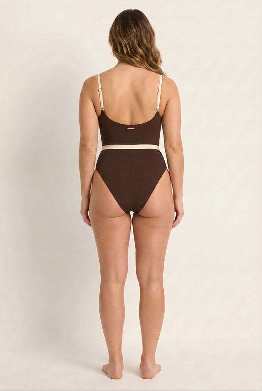 Woman wearing a brown swimsuit against a plain background