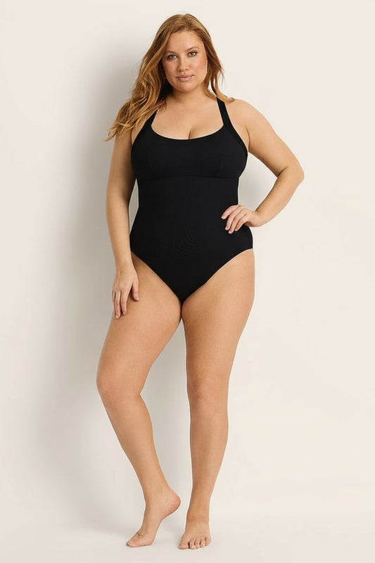 Woman wearing a black swimsuit against a plain background