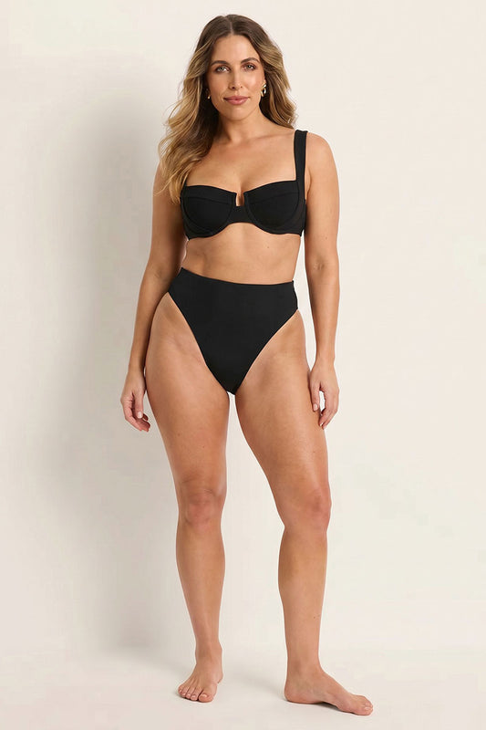 Woman wearing a black bikini set against a plain background
