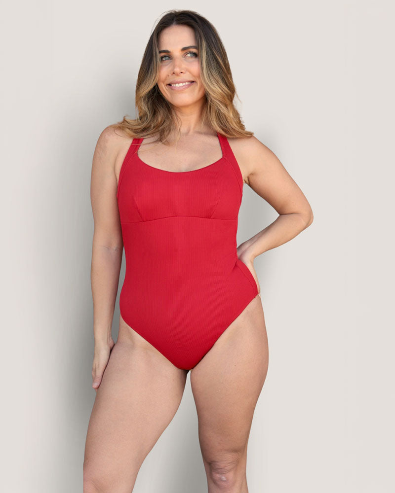 Woman in a Fearless red supportive bust and one piece swimsuit.