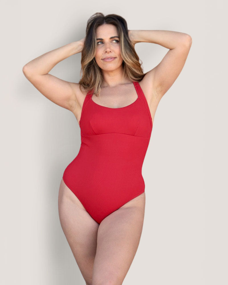 Woman in a Fearless red supportive bust and one piece swimsuit.