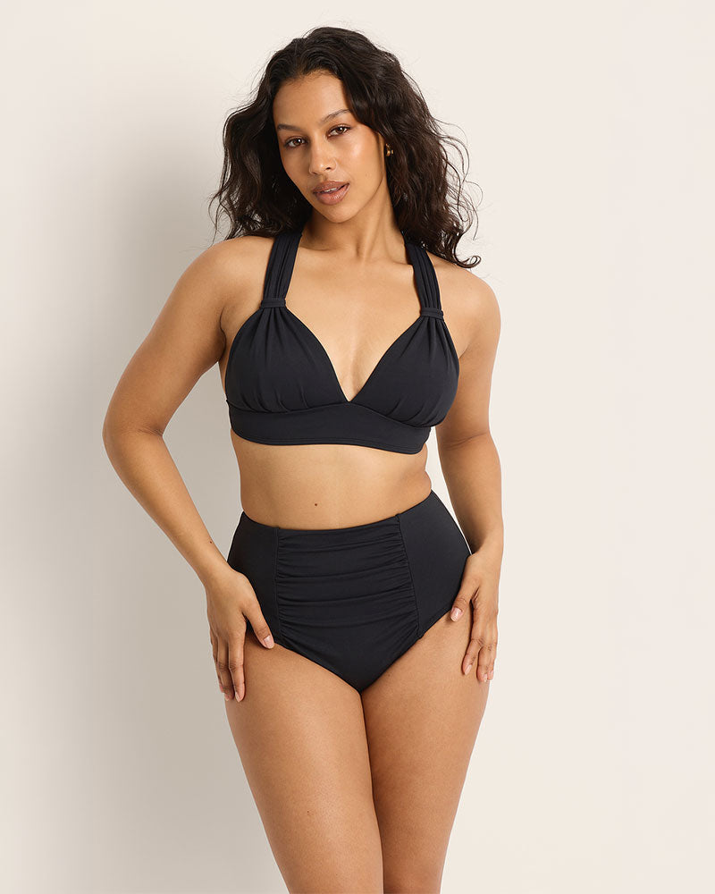 Woman wearing a Fearless supportive bust and high waist black bikini against a plain background.
