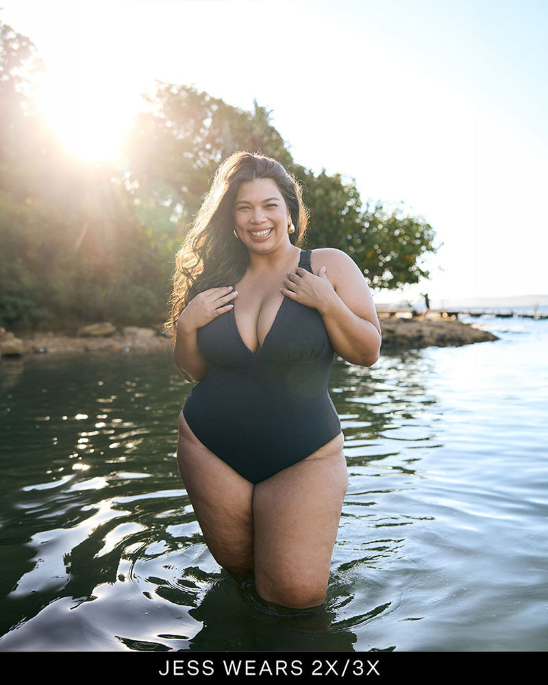 Woman wearing a full coverage, supportive bust black swimsuit in the ocean.