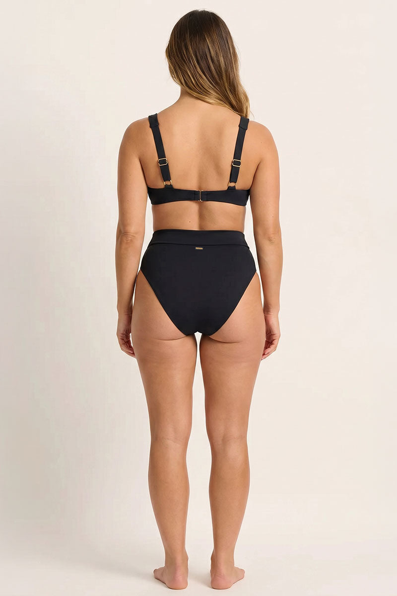 Woman wearing a black bikini set on a plain background