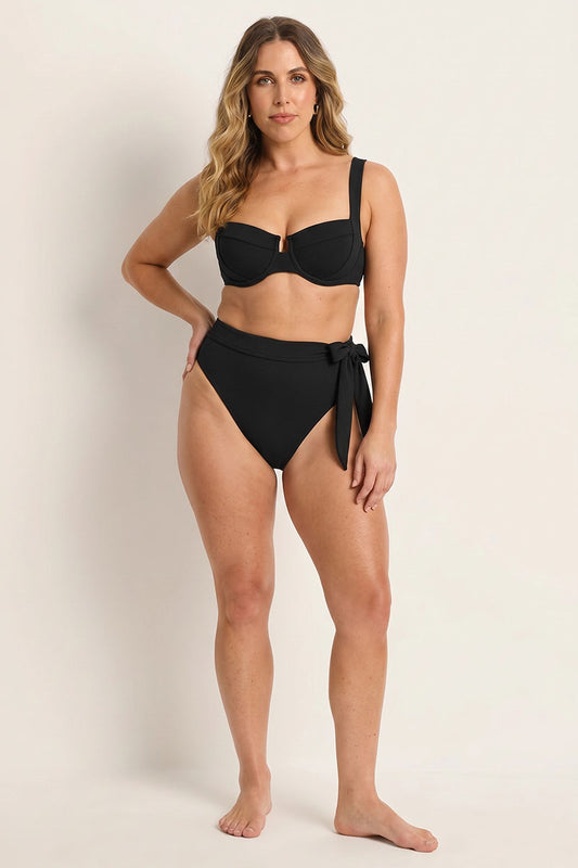 Woman wearing a black bikini with a plain background