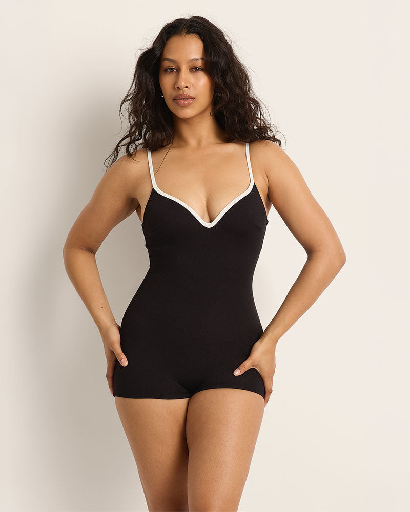Woman wearing a black and white supportive swimsuit with white trim against a plain background