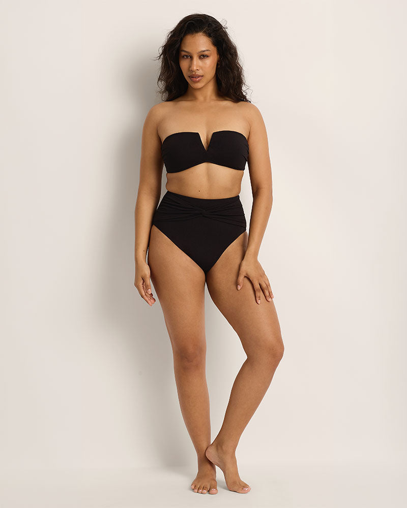 Woman wearing a black bikini set against a plain background