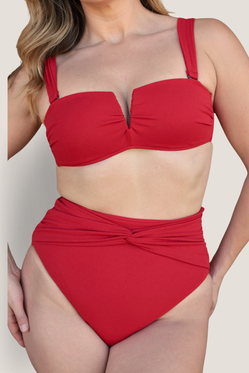 A woman models the Fearless au Icon Bikini Top in red, featuring wide straps and a twist waistband, crafted from recycled LuxeCrinkle fabric, against a plain light background.