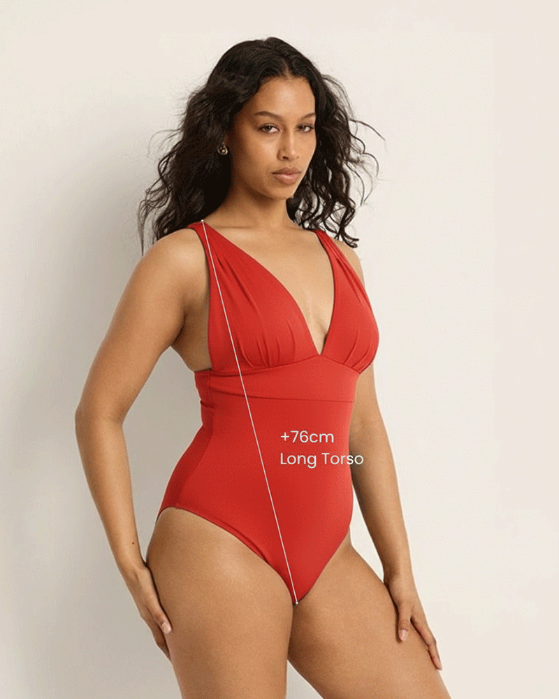 Brunette woman wearing a supportive bust red Fearless swimsuit against a plain background. Swimsuit has 360 degree compression mesh.