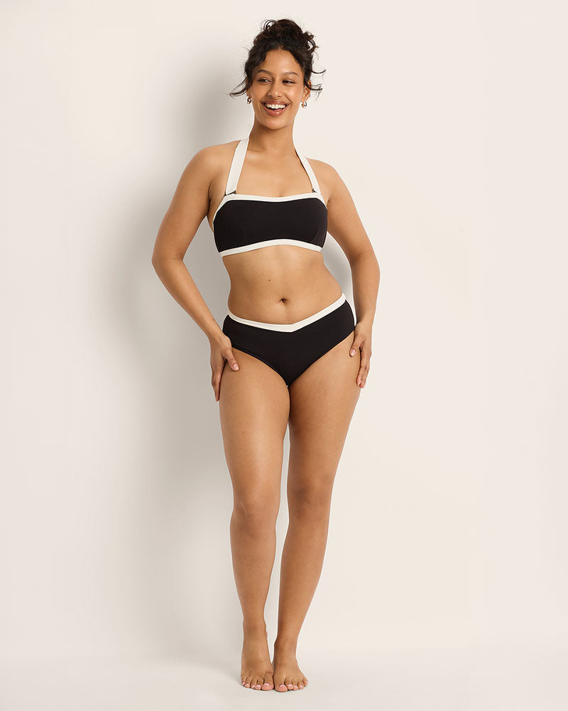 Woman wearing a black and white bikini against a plain background