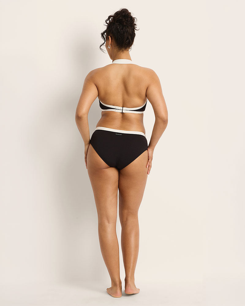 Person wearing a black and white bikini against a plain background