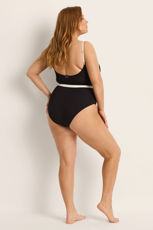 Woman wearing a supportive black swimsuit with white trim against a plain background.