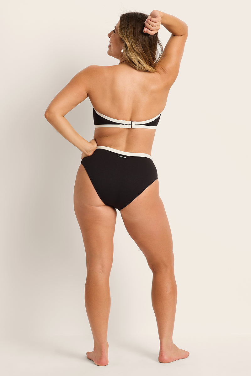 Woman wearing a black and white bikini against a plain background