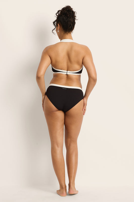 Person wearing a black and white bikini against a plain background