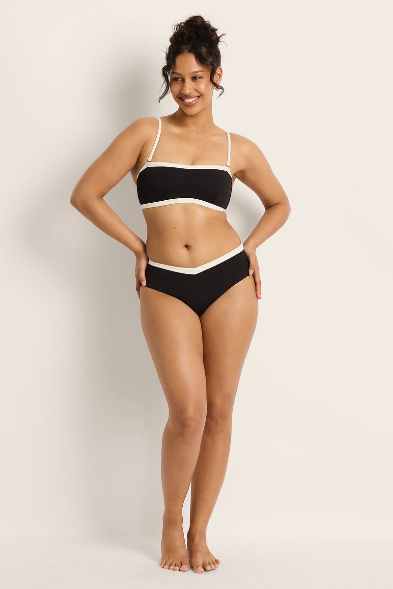 Woman wearing a black and white bikini against a plain background