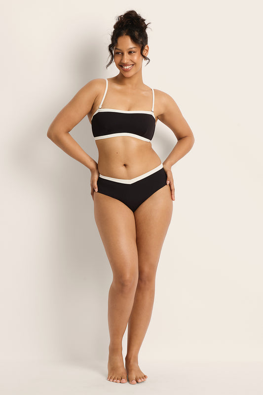 Woman wearing a black and white bikini against a plain background