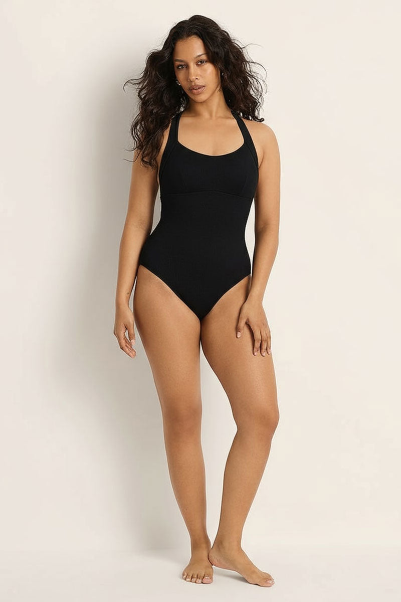 Woman wearing a black swimsuit against a plain background