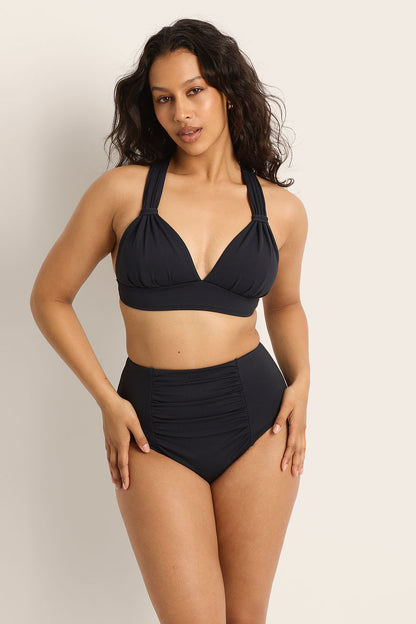 Woman wearing a black bikini set against a plain background
