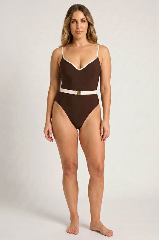 Woman wearing a brown swimsuit with a white belt on a plain background