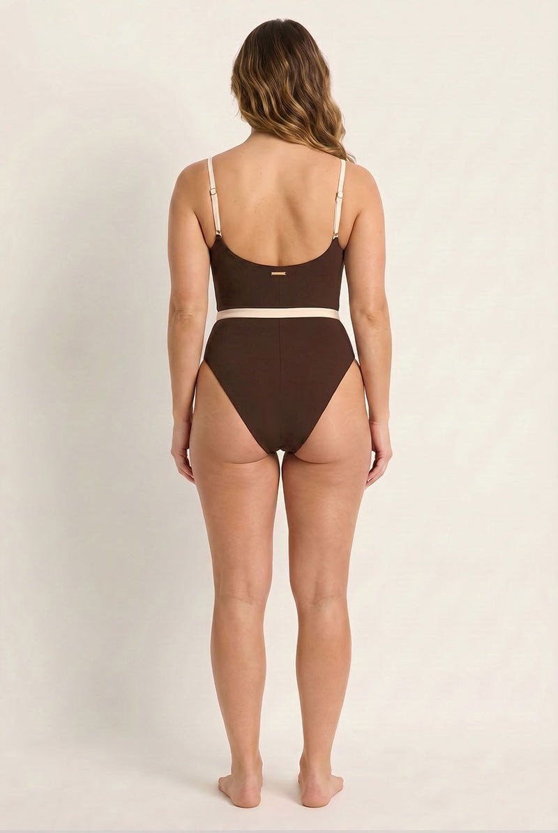 Woman wearing a brown swimsuit against a plain background