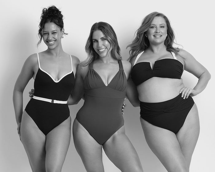 Three women wearing black swimsuits on a plain background
